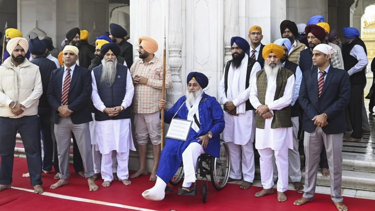 पैर पर प्लास्टर, गले में तख्ती, हाथ में भाला… व्हील चेयर पर बैठ ‘पहरेदार’ बने सुखबीर सिंह बादल: जानिए किन गलतियों की मिली है सजा, क्यों शौचालय की सफाई से मिली माफी