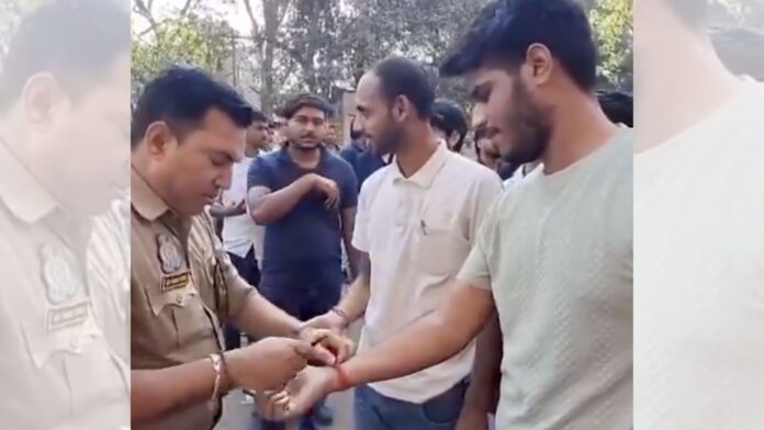 अभ्यर्थी का कलावा काटता पुलिसकर्मी